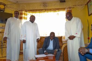 Rigathi signing visitors book when he was hosted by Father Maina recently.