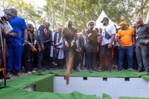 President Ruto throws soil into the grave of Raila Odinga.
