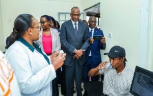 Samson Mutua receives the jab as Health Cabinet Secretary Aden Duale looks on. (Photo: MoH)